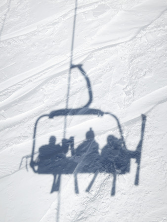 Shadow of skiers in ski lift chairの写真素材