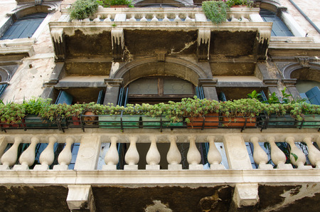 Old building facade with big balcony, flowers and arches, shot from under the balcony, Venice , Italy.の写真素材