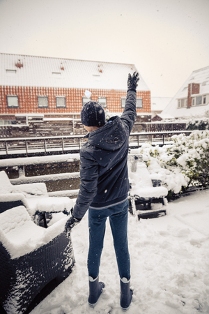 Little boy throws snowballs in a backyard, enjoying the first snow in late autumn.の写真素材