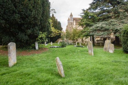 Small cemetery with green grass, with a church in the background.の写真素材