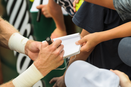 Tennis player signs autograph on a notebook after win, closeup photo showing man making signature.のeditorial素材