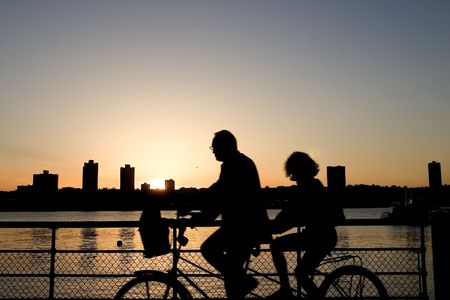 Two cyclists on the tandem bike riding along Hudson Riverの写真素材