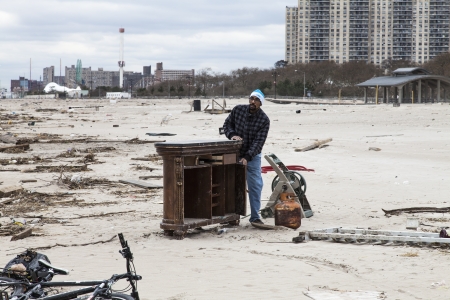 NEW YORK - NOVEMBER 1, 2012  Unidentifiying beach goer cheks debris on the Brighton Beach after Hurricane Sandy hit Brooklyn area on November 1, 2012, Brooklyn, NYのeditorial素材