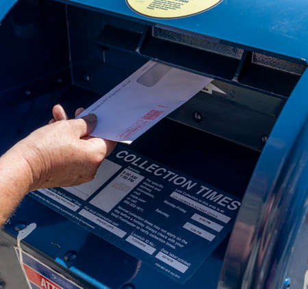 Brooklyn, NY, USA - August 18, 2020: Unidentified person drops a letter in United Siates Postal Sercice Mailbox amid postal crisis, COVID-19 and upcoming elections.のeditorial素材