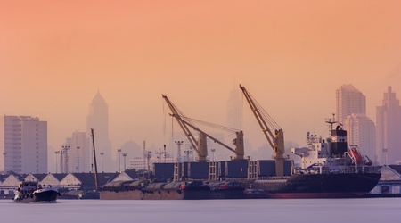 Container Cargo freight ship with working crane bridge in shipyard at dusk for Logistic Import Export backgroundのeditorial素材