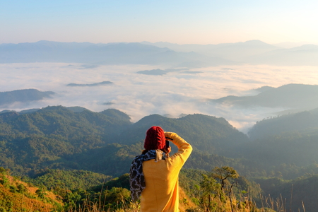 Hiker with photo camera standing on top of the mountainの写真素材