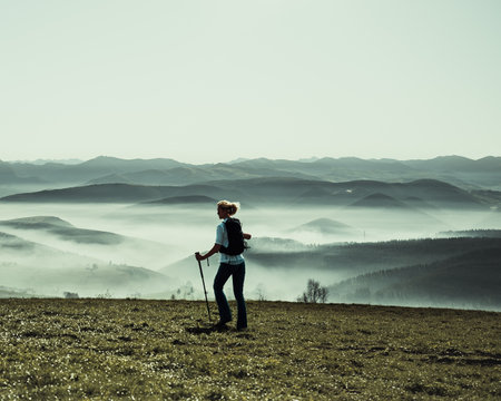 Hiker stands in awe at breathtaking viewpoint. Nature's grandeur unfolds, captivating the soul. A moment of serenity and adventure amidst a stunning landscapeの写真素材