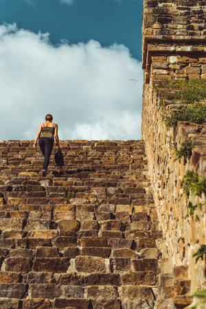 Amid Palenque's ancient ruins, a woman ascends worn stairs, her presence a testament to the enduring...