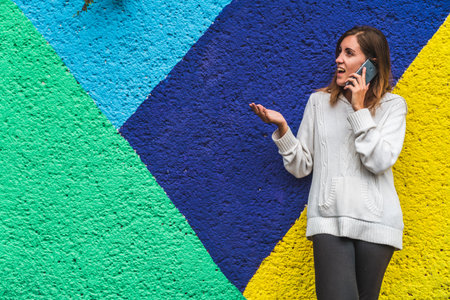 A woman's beaming smile brightens a phone conversation against an abstract backdrop of vibrant...