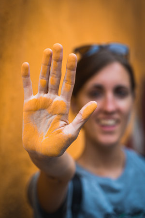 With a radiant smile, a woman proudly presents her hand, adorned in a vibrant cloak of golden dust. A testament to her diligent work, it symbolizes joy and the beauty of dedicated craftsmanshipの写真素材