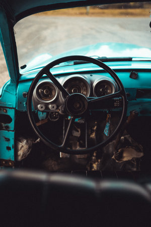 A man investigates beneath a vintage Cuban red car, unraveling its mechanical secrets. They are in a stone-made street of Trinidad, Cubaの写真素材