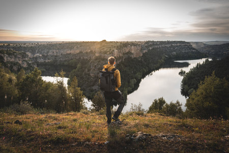 Awe-struck hiker contemplates nature's grandeur, gazing at the river winding through the majestic canyonの写真素材