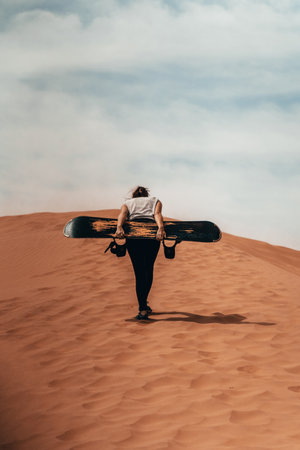 Snowboarding on sand: A woman gracefully carves through a dune, blending two worlds of adventure into a captivating display of skill and excitement.の写真素材