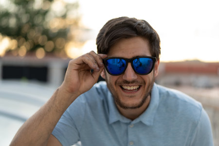 Portrait of a young man with glasses: A sunny day frames the confident gaze of a stylish young man, capturing his youthful charm.の写真素材