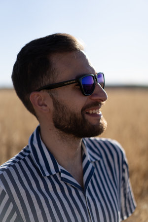 Portrait of a young man with glasses: A sunny day frames the confident gaze of a stylish young man, capturing his youthful charm.の写真素材
