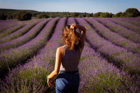 A woman gracefully posing amidst blooming lavender fields, creating a picturesque scene of beauty and serenity.の写真素材