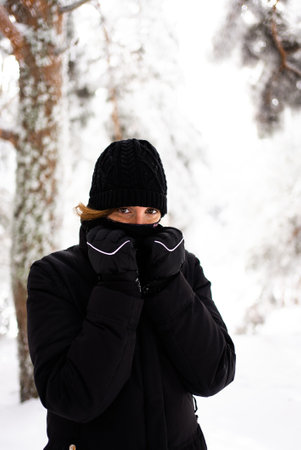 A woman bundled up in a thick black coat, braving the cold weather with determination and resilience.の写真素材
