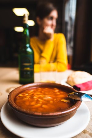 Asturian delight, Fabada Asturiana, a traditional Spanish dish featuring white beans, sausages, and pork, accompanied by a bottle of fine wineの写真素材