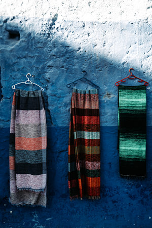 Scarfs on vibrant blue wall: Colorful scarfs adorn a captivating blue backdrop, creating a visually dynamic display.の写真素材