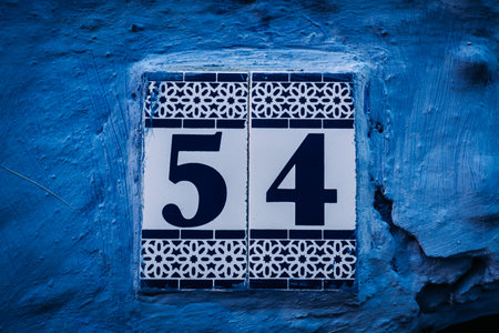 Vibrant blue house post: Numbers adorn this eye-catching house post, creating an intriguing focal point against the vivid blue backdrop.の写真素材