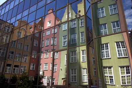 Colorful tenement houses reflected in windows of modern building in Gdansk
