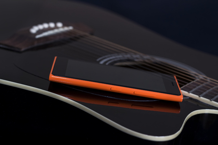 Mobile phone on black guitar, old and new connection concept