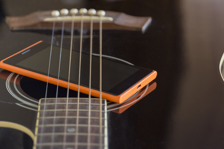Mobile phone on black acoustic guitar, old and new connection conceptの写真素材