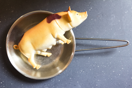 Fake and processed food, nutrition concept, plastic toy pig on the panの写真素材