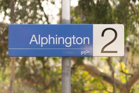 Melbourne, Australia - May 21st 2019: On platform sign for Alphington Train Station, which is on the Hurstbridge Line. Sign and pole infront of blurred leafy background.のeditorial素材