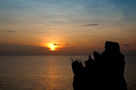 Silhouette of a single rock on the sea sunset backgroundの写真素材