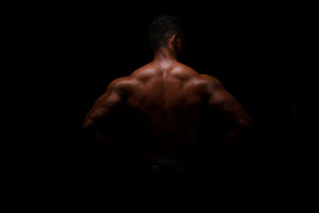 Silhouette of young athlete bodybuilder man on blackの写真素材