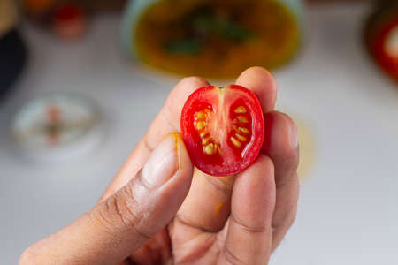 cut cherry tomato in hand isolated on light backgroundの写真素材
