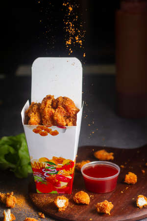 Paper container with fried crispy chicken popcorn nuggets on marble background.Copy spaceの写真素材