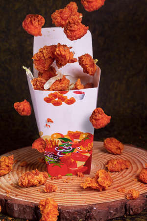 Paper container with fried crispy chicken popcorn nuggets on marble background.Copy spaceの写真素材