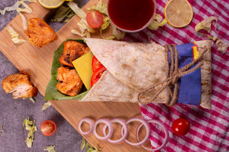 Fresh chicken seekh roll with fresh tomatos, salad, cheese and onions isolated on bright blue background. Side view.selective focusの写真素材