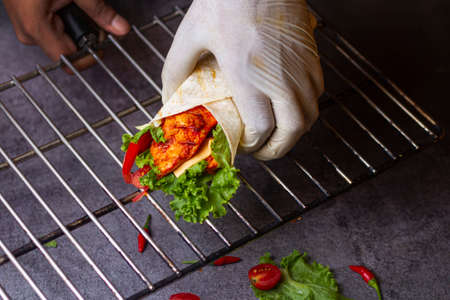 Fresh chicken seekh roll with fresh tomatos, salad, cheese and onions isolated on bright blue background. Side view.selective focusの写真素材