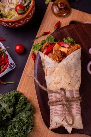 Fresh chicken tikka roll with fresh tomatos, salad, cheese and onions isolated on bright blue background. Side view.selective focusの写真素材
