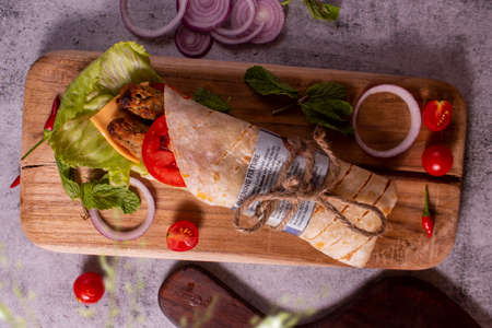 Fresh sausage roll with fresh tomatos, salad, cheese and onions isolated on bright blue background. Side view.cope space.selective focusの写真素材