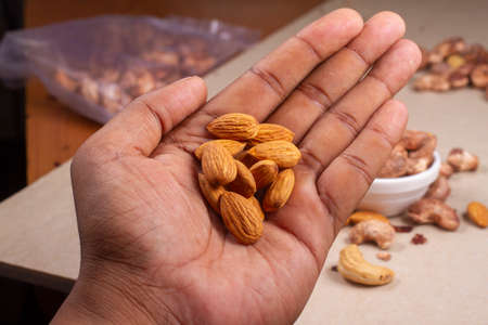 Roasted almond and cashew nuts in hand on light background isolation.