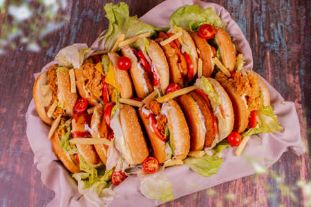 Different hamburgers seen from above with french fries in the middle of the sandwiches. Basket with cloth under the burgers.の写真素材