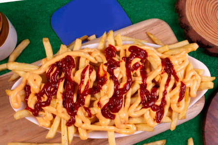 Dish of CHEESY FRIES at cafe restaurant. American fast food dish, consisting of french fries covered...