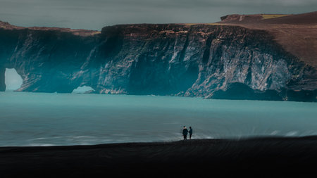 Man and woman standing on the edge of a cliff in Iceland.