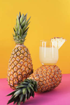 Freshly squeezed pineapple juice in a glass glass on a lying pineapple, next to pineapple, bright...