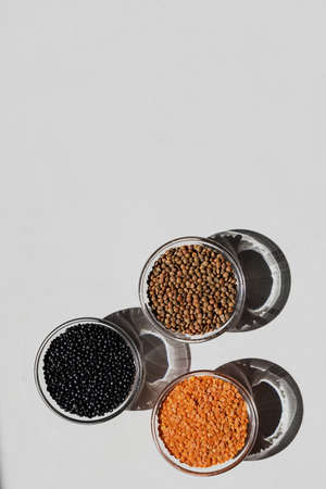 Red, black, brown seeds of dry lentils on light background
