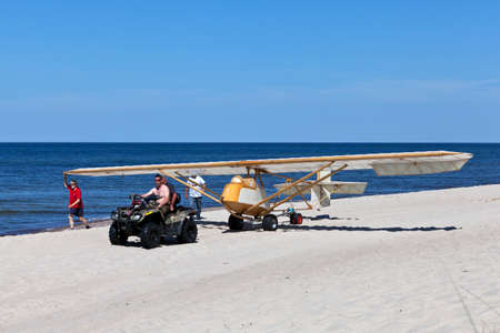 A quad bike pulls a motorless glider on the beachのeditorial素材