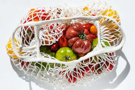 Colorful tomatoes of different varieties in white mesh zero-waste
