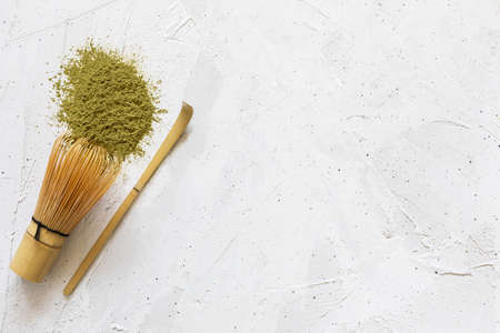whisk and spoon with scattered dry matcha tea powder on white backgroundの写真素材