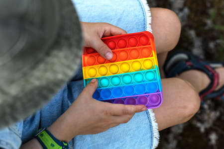 A child on the street clicks on rainbow anti-stress pop it