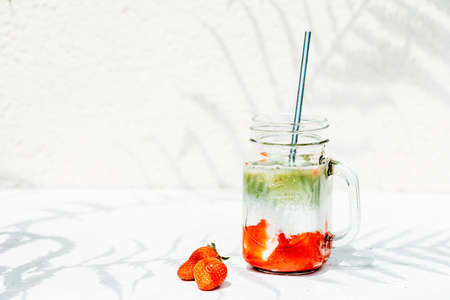 Strawberry matcha latte drink under bright sun and shade from fernの写真素材