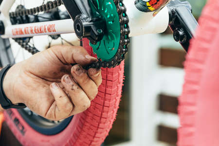 A man repairs a chain on a bicycle